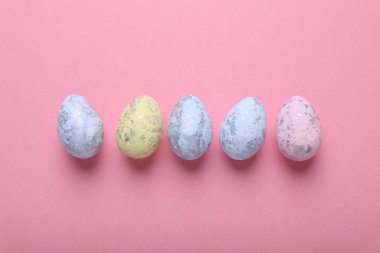 Many painted Easter eggs on pink background, flat lay