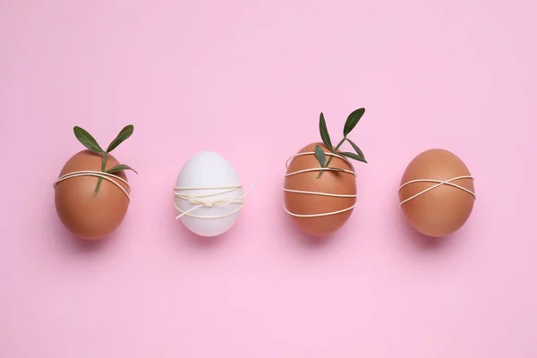 Beautifully decorated Easter eggs on pink background, flat lay