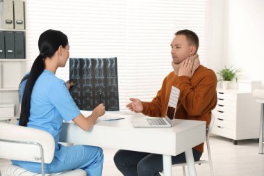 Doctor with neck MRI image consulting patient in clinic