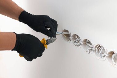 Handyman installing sockets in white wall, closeup