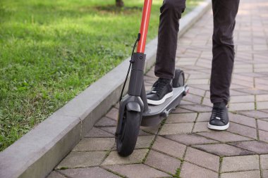 Parkta modern elektrikli scooter kullanan adam, yakın plan.