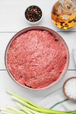 Bir kase taze kıyma ve malzemeler beyaz ahşap masa üzerinde, düz yatıyordu.