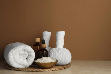 Composition with different spa products on beige table against brown background. Space for text