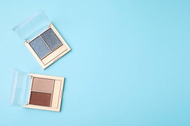 Açık mavi arka planda güzel göz farı paletleri, düz yatış. Metin için boşluk