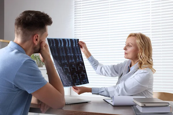Doctor with MRI image consulting patient in clinic