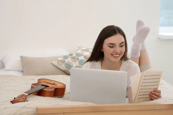 Woman learning to play ukulele with online music course at home. Space for text