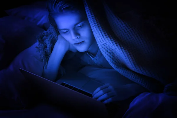 Интернет Зависимость Мальчик Подросток Использует Ноутбук Одеялом Кровати Ночью Тонированные — стоковое фото