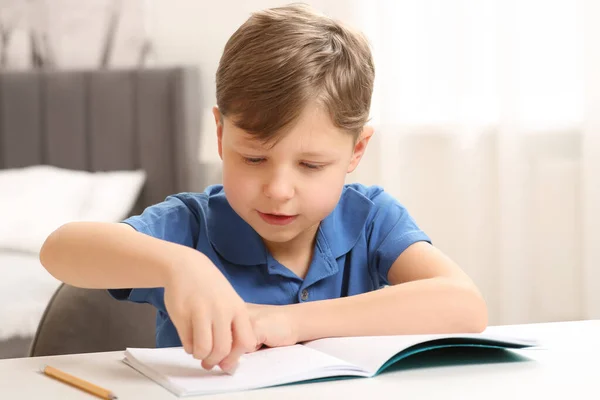 Kleiner Junge Löscht Fehler Seinem Notizbuch Weißen Schreibtisch Drinnen — Stockfoto