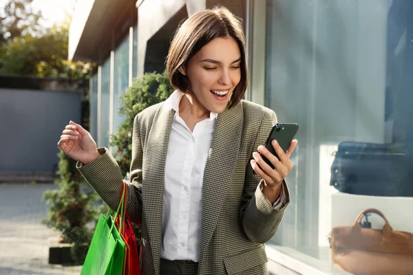 Sonderaktion Emotionale Junge Frau Mit Einkaufstaschen Und Smartphone Schaufensternähe — Stockfoto