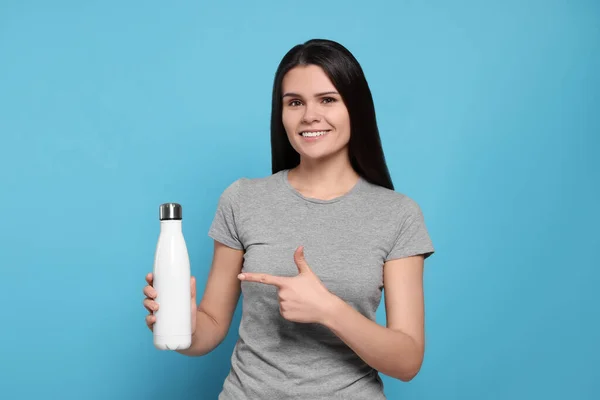 Junge Frau Mit Thermoflasche Auf Hellblauem Hintergrund — Stockfoto