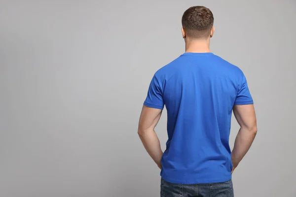 Mężczyzna Niebieskiej Koszulce Jasnoszarym Tle Widok Tyłu Makieta Projektowania — Zdjęcie stockowe