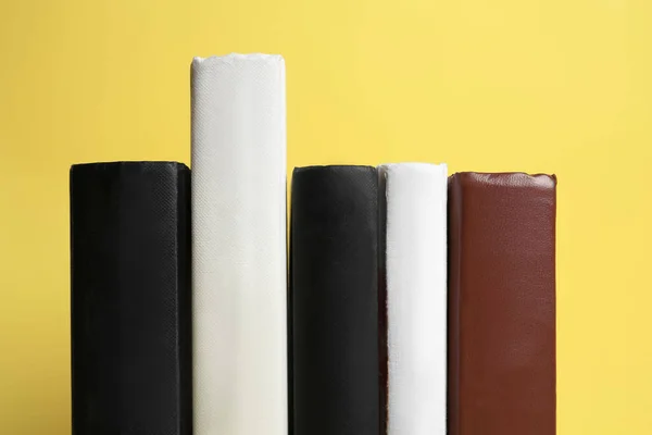Collection of hardcover books on yellow background, closeup