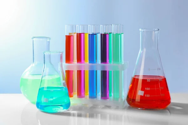 Diferentes Cristalería Laboratorio Con Líquidos Colores Mesa Blanca Sobre Fondo — Foto de Stock