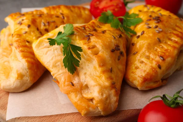 stock image Fresh delicious puff pastry with cheese, tomatoes and parsley on wooden board, closeup