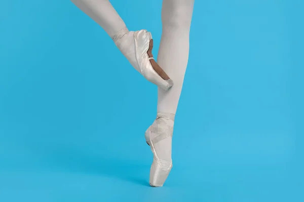 穿着尖皮鞋的年轻芭蕾舞演员在浅蓝色背景下练习跳舞 — 图库照片