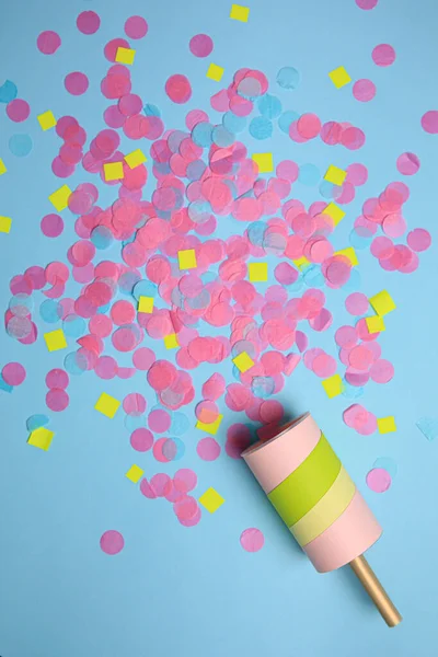 Party popper with bright confetti on light blue background, flat lay