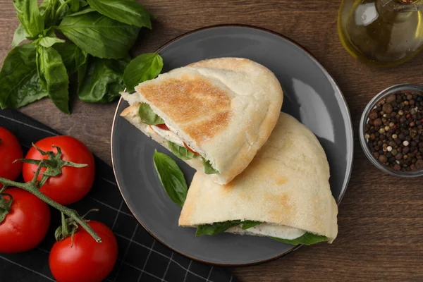 モッツァレラチーズとおいしいピタのサンドイッチ 木のテーブルの上にトマトとバジル フラットレイアウト — ストック写真