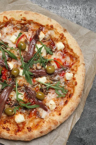 Stock image Tasty pizza with anchovies, arugula and olives on grey table, top view