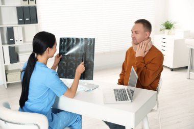 Doctor with neck MRI image consulting patient in clinic