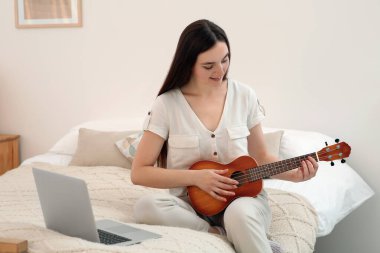 Kadın evde internet müzik kursuyla gitar çalmayı öğreniyor. Hobi zamanı.