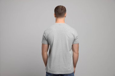 Açık gri arka planda beyaz tişört giyen bir adam. Tasarım için model