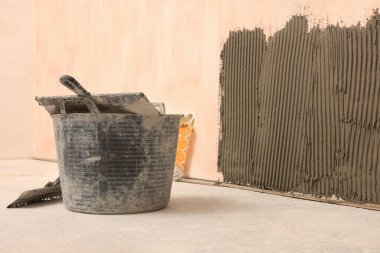 Bucket near white wall with adhesive mix for tile installation indoors