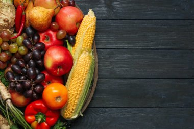 Farklı taze sebzeler ve siyah ahşap masadaki meyveler, yazı için yeri olan üst manzara. Çiftçi hasat ediyor.