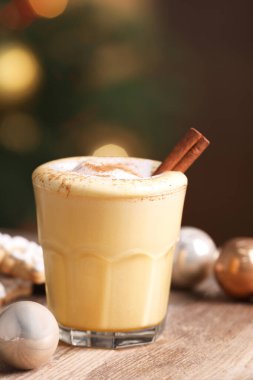 Tarçınlı yumurta likörü, kurabiyeler ve ahşap masada bulanık ışıklara karşı takılar.