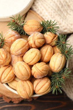 Bir kase lezzetli fındık şekilli kurabiye ve ahşap masanın üzerinde köknar ağacı dalları.