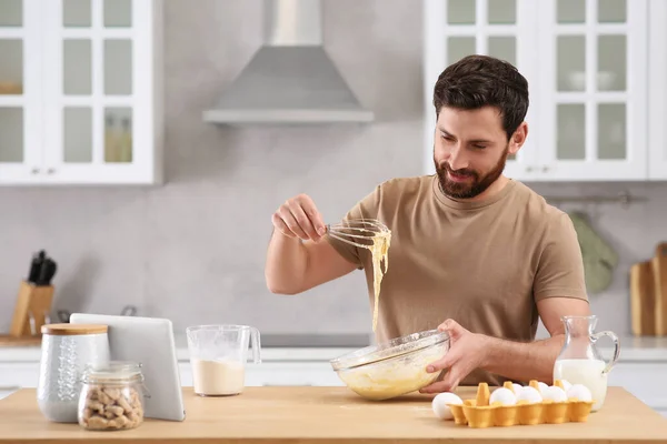 stock image Man making dough while watching online cooking course via tablet in kitchen