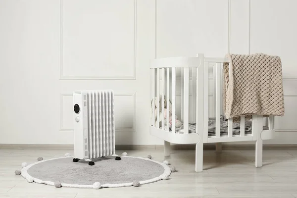 地毯和婴儿床上的现代便携式电热器 — 图库照片