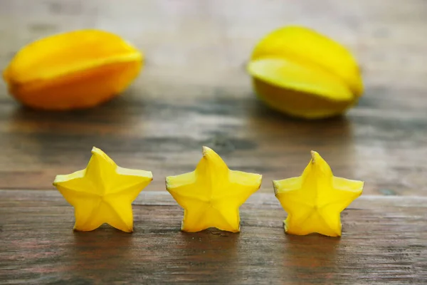 stock image Delicious cut and whole carambolas on wooden table. Exotic fruit