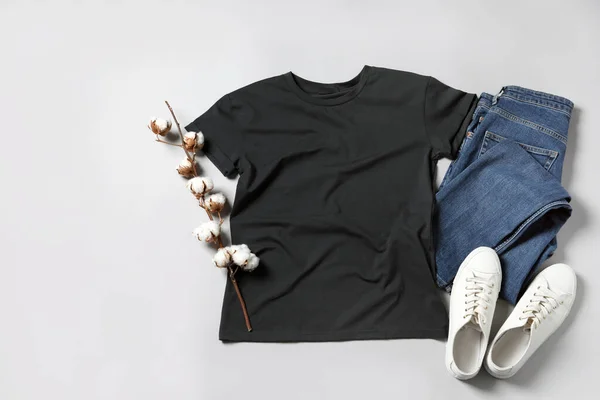 ライトグレーの背景にスタイリッシュなTシャツ ジーンズ スニーカー フラットレイ — ストック写真