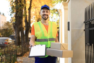 Üniformalı kurye sipariş makbuzunu ve paketleri dışarıda tutuyor.