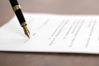 Tahta masadaki dolmakalemle belgeye yazmak, yakın plan. Noter sözleşmesi