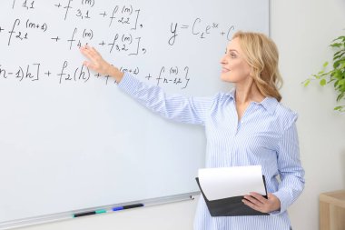 Profesör pano ile sınıfta beyaz tahtanın yanında konferans veriyor.