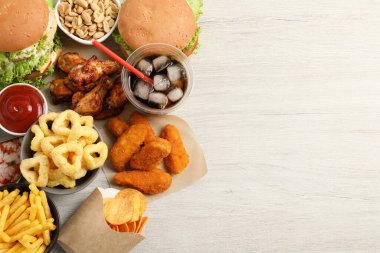 Kızarmış patatesler, hamburgerler ve diğer fast food beyaz ahşap masa üzerinde, düz bir şekilde uzanıyordu.