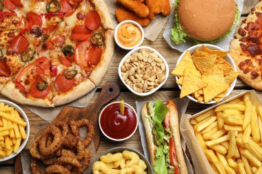 Pizza, patates kızartması ve ahşap masada diğer fast food 'lar.