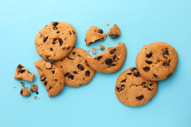 Açık mavi arka planda bir sürü çikolata parçacıklı kurabiye, düz uzanmış.