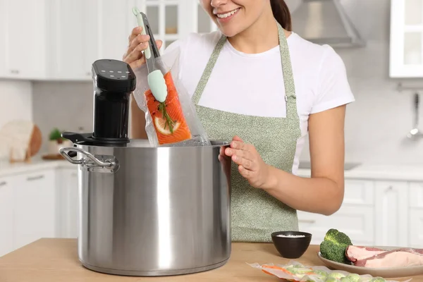 掃除機を入れたサーモンを鍋に入れて台所でこんな脇の鍋で閉じ込めた女 熱浸循環器 — ストック写真