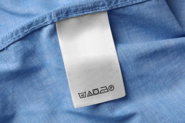 White clothing label on light blue garment, closeup