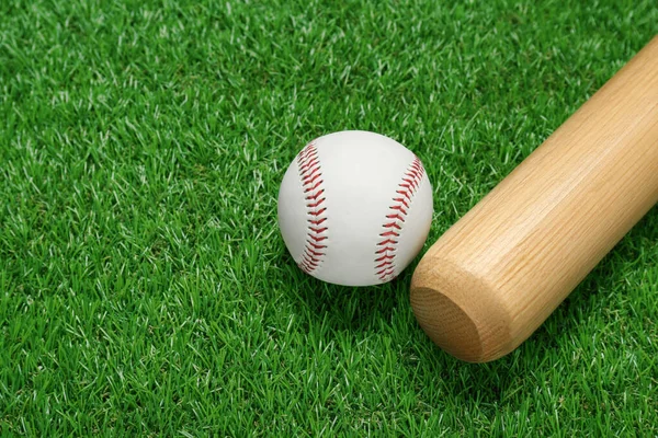 緑の芝生の上で木製の野球バットとボールを閉じます スポーツ用具 — ストック写真