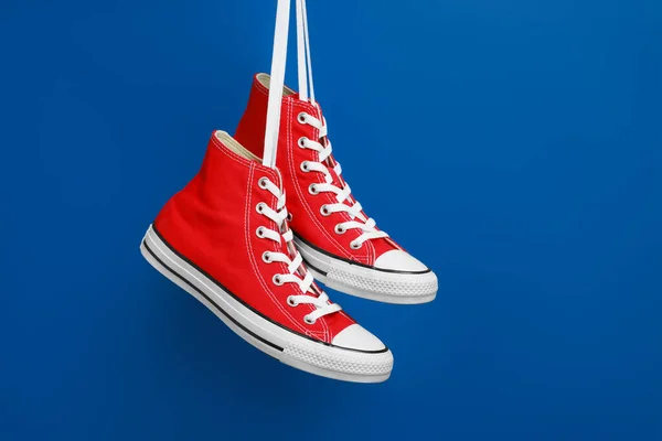 Een Paar Nieuwe Stijlvolle Rode Sneakers Hangend Aan Veters Tegen — Stockfoto