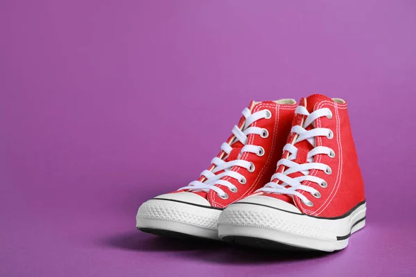 stock image Pair of new stylish red sneakers on purple background. Space for text