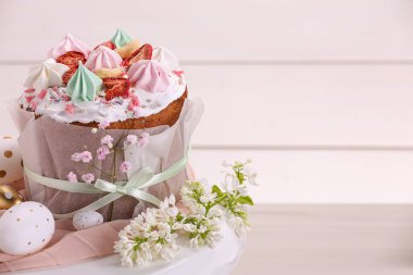 Traditional Easter cake with meringues and painted eggs on white wooden table, space for text