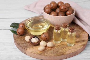 Lezzetli organik Macadamia fındıkları ve beyaz ahşap masa üzerindeki kozmetik yağı.