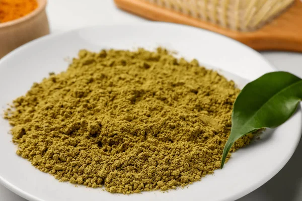 Henna powder and green leaf on white table, closeup. Natural hair coloring