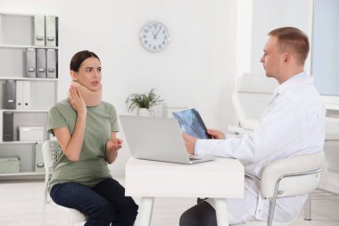 Doctor with neck MRI image consulting patient in clinic