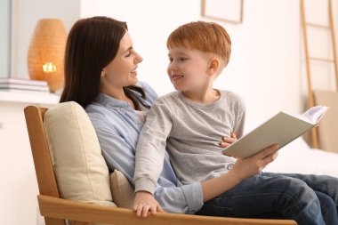 Anne, çocuğuyla birlikte evde kitap okuyor.
