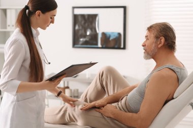 Klinikteki profesyonel kadın ortopedist hastaya danışmanlık yapıyor.